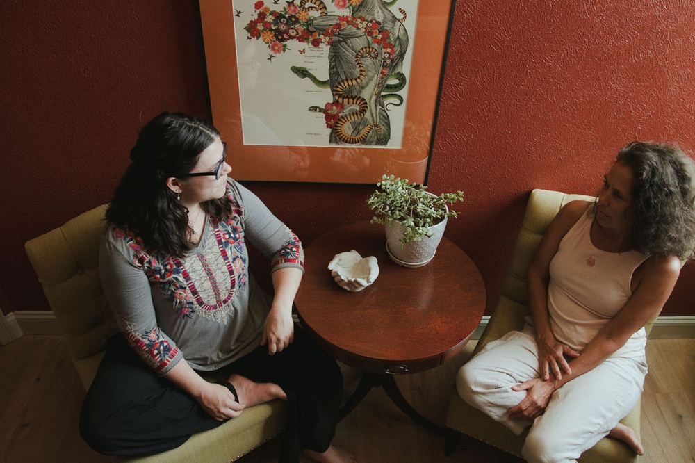 Gabrielle Díona seated with a client in her intake room, mid-conversation