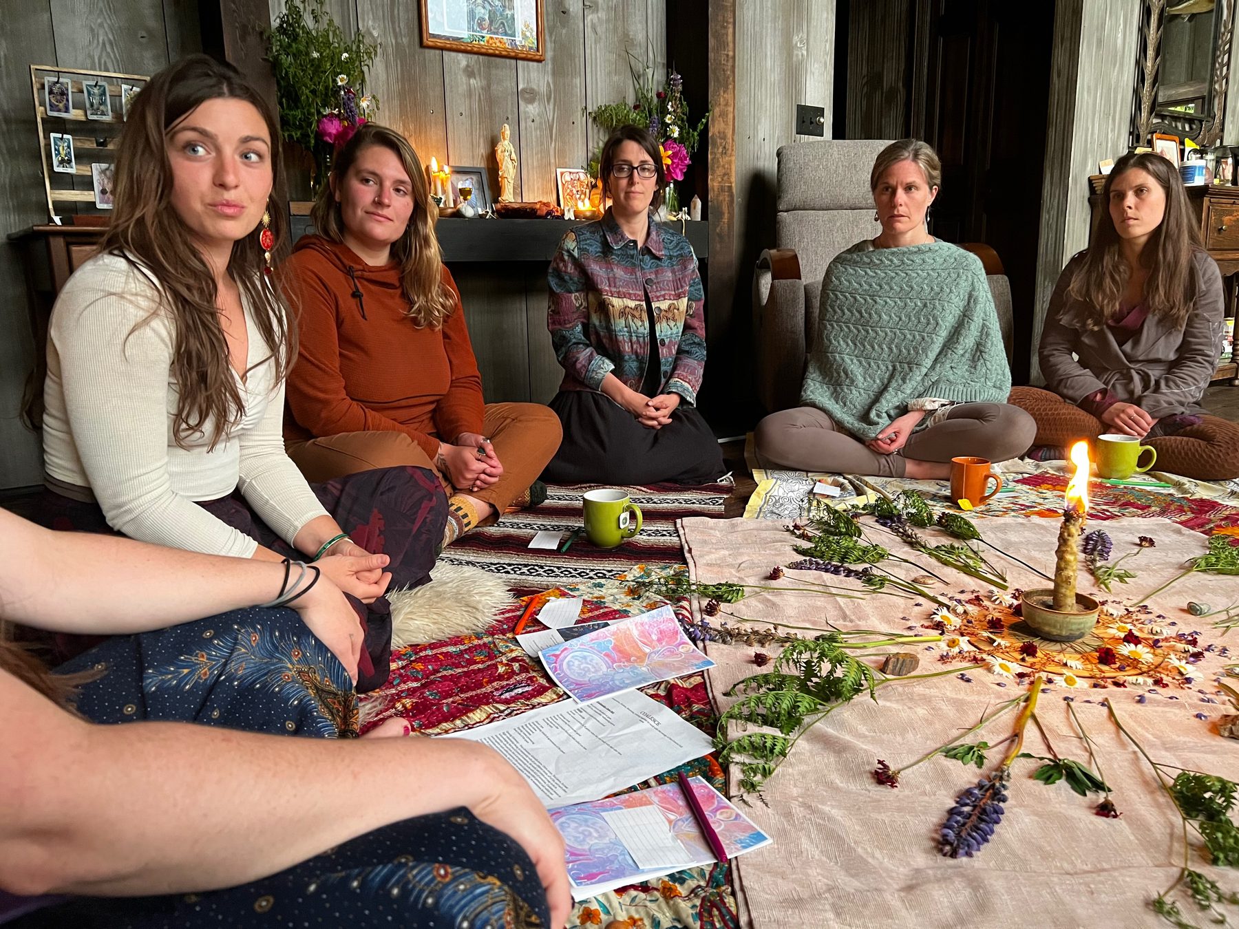 A retreat group gathered in candlelight around a floral mandala altar